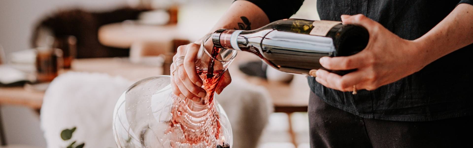 Vanessa Stoltz, Restaurant Manager and Head Sommelier at Pine in Northumberland, pours red wine into a decanter in the restaurant dining room.